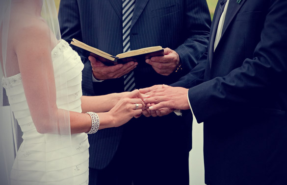 Bride and Groom Holding Hands With Each Other While Priest Reading The Wedding Vows.